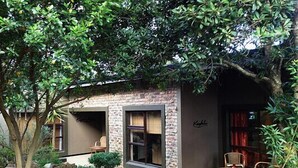 A cozy building with a stone facade, a large window, and a small porch area. - Clairewood (Wilderness)