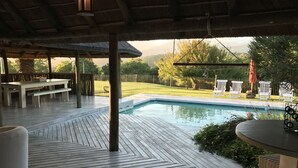 A wooden deck with a pool, outdoor seating, and a view of a fenced yard. - Clairewood (Wilderness)