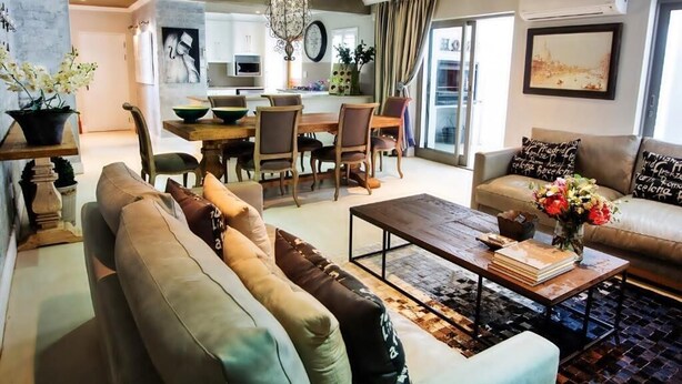 Een moderne woonkamer met een bank, salontafel en een eethoek.
