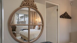 Een slaapkamer met een grote ronde spiegel, een gestoffeerde bank en uitzicht op een balkon.