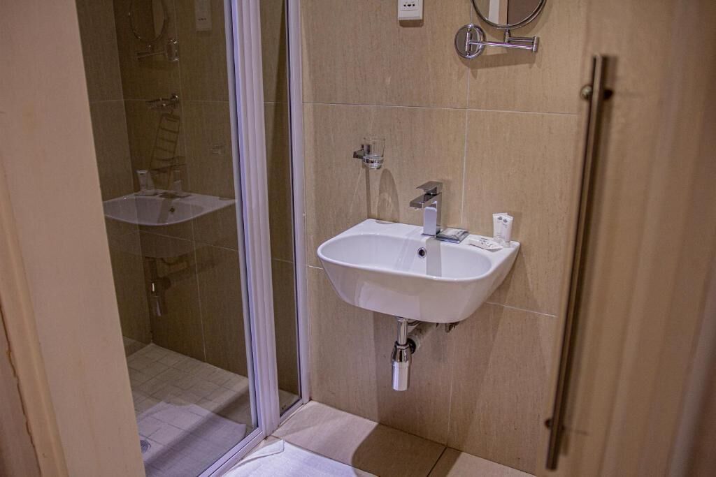 Een badkamer met een glazen douchecabine, een wastafel en een spiegel aan de muur.