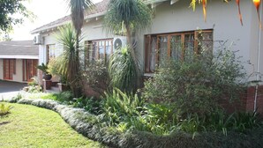 A house with a well-maintained garden, large windows, and a tiled roof. - Thembelihle Guest House (Pietermaritzburg)