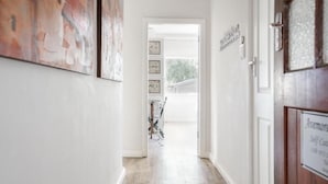 A hallway with a wooden floor, framed pictures on the walls, and a door with a sign. - Avemore Vredehof No 1- with backup power (Stellenbosch)