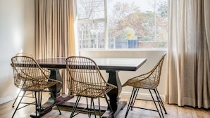 A dining area with a dark wooden table and four wicker chairs. - Avemore Vredehof No 1- with backup power (Stellenbosch)