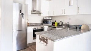 A modern kitchen with white cabinets, stainless steel appliances, and a granite countertop. - Avemore Vredehof No 1- with backup power (Stellenbosch)