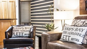 A modern living room with leather sofas, a coffee table with books, and a striped wall.