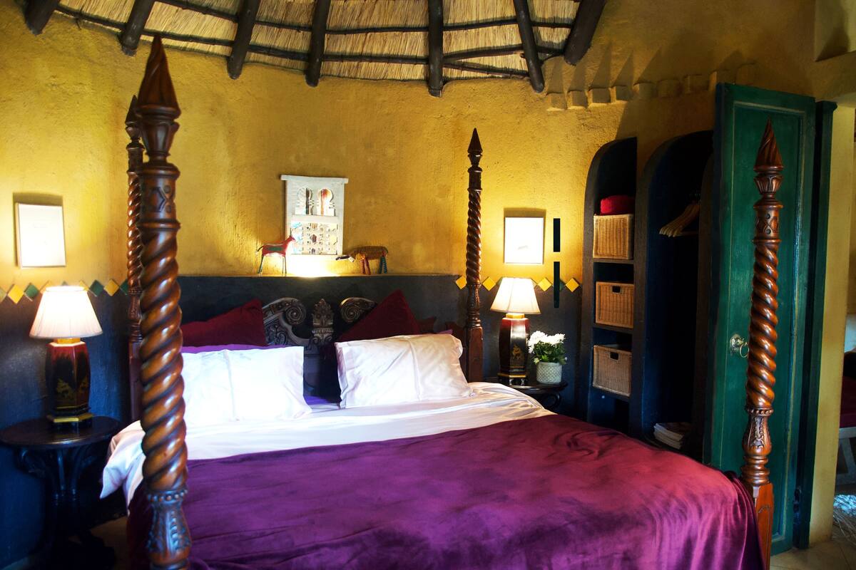 A bed with a wooden headboard, a purple bedspread, and a nightstand with a lamp.