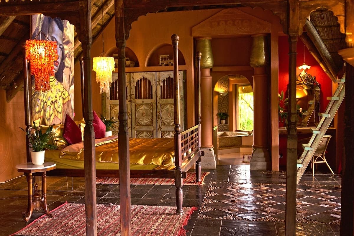 A traditional room with a bed, a chandelier, and a staircase.