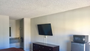 A hotel room with a bed, a dresser, a television mounted on the wall, and a microwave on a small table. - Super Stay Inn (North Little Rock)