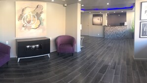 A reception area with a modern design, featuring a fireplace, two purple armchairs, and contemporary artwork on the walls. - Super Stay Inn (North Little Rock)