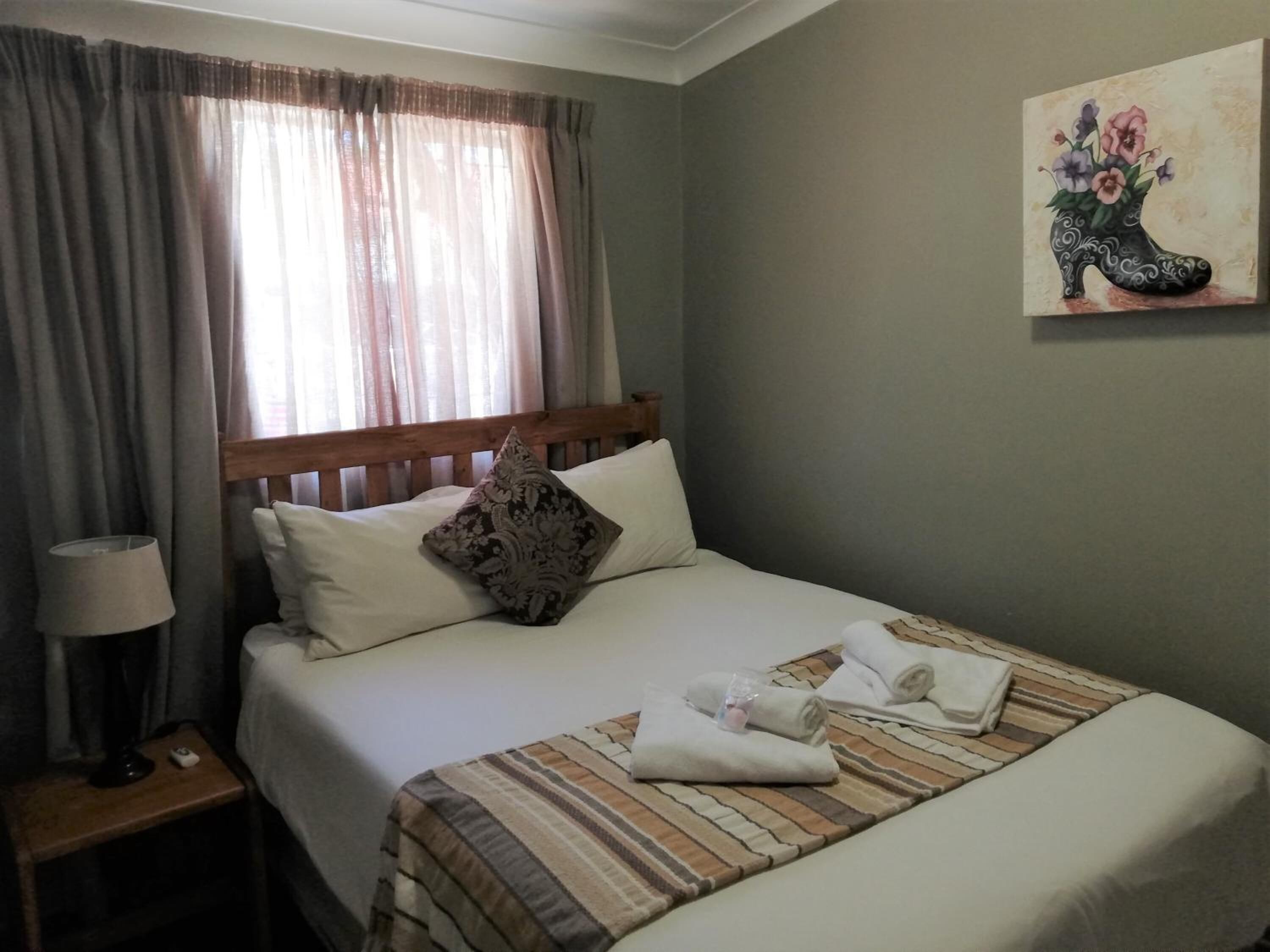 Una cama bien hecha con una manta a rayas, una almohada y una toalla enrollada sobre la cama.