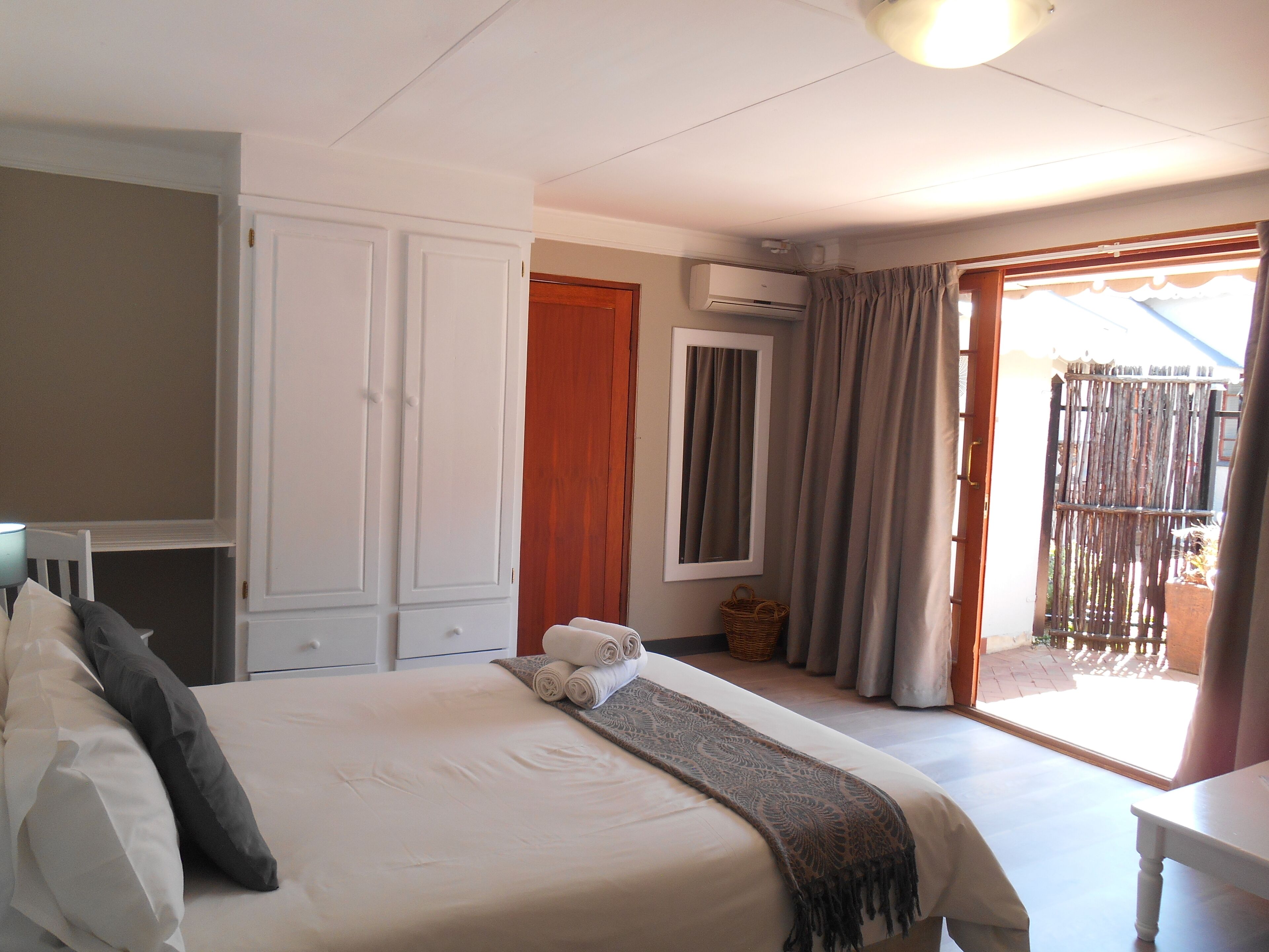 Une chambre à coucher comprenant un lit, une armoire, un appareil de climatisation, un miroir et une vue sur l’extérieur.