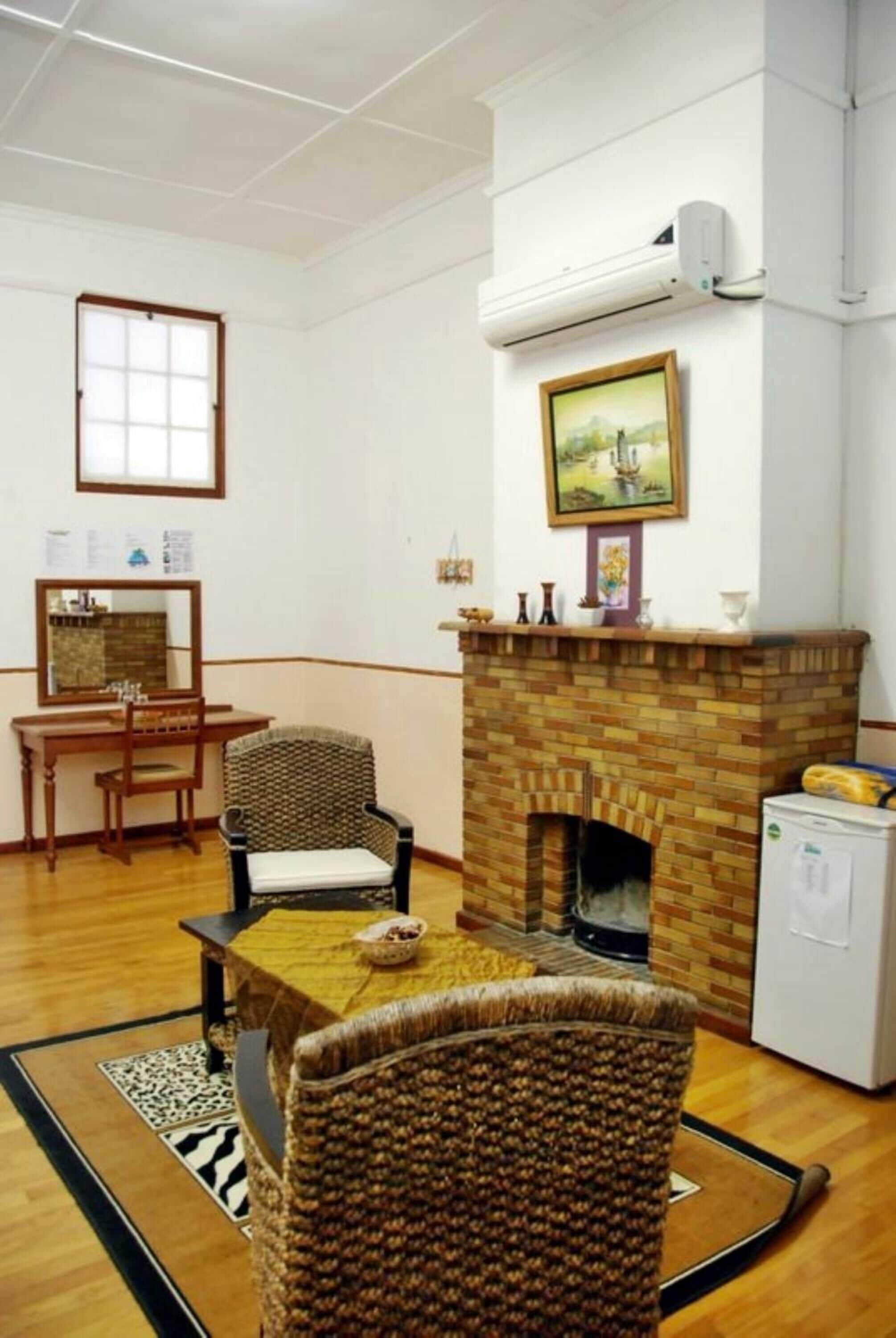 Una habitación con chimenea de ladrillo, una mesa de comedor con sillas, un refrigerador pequeño y una ventana con vistas al paisaje.