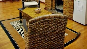 Una habitación con chimenea de ladrillo, una mesa de comedor con sillas, un refrigerador pequeño y una ventana con vistas al paisaje.