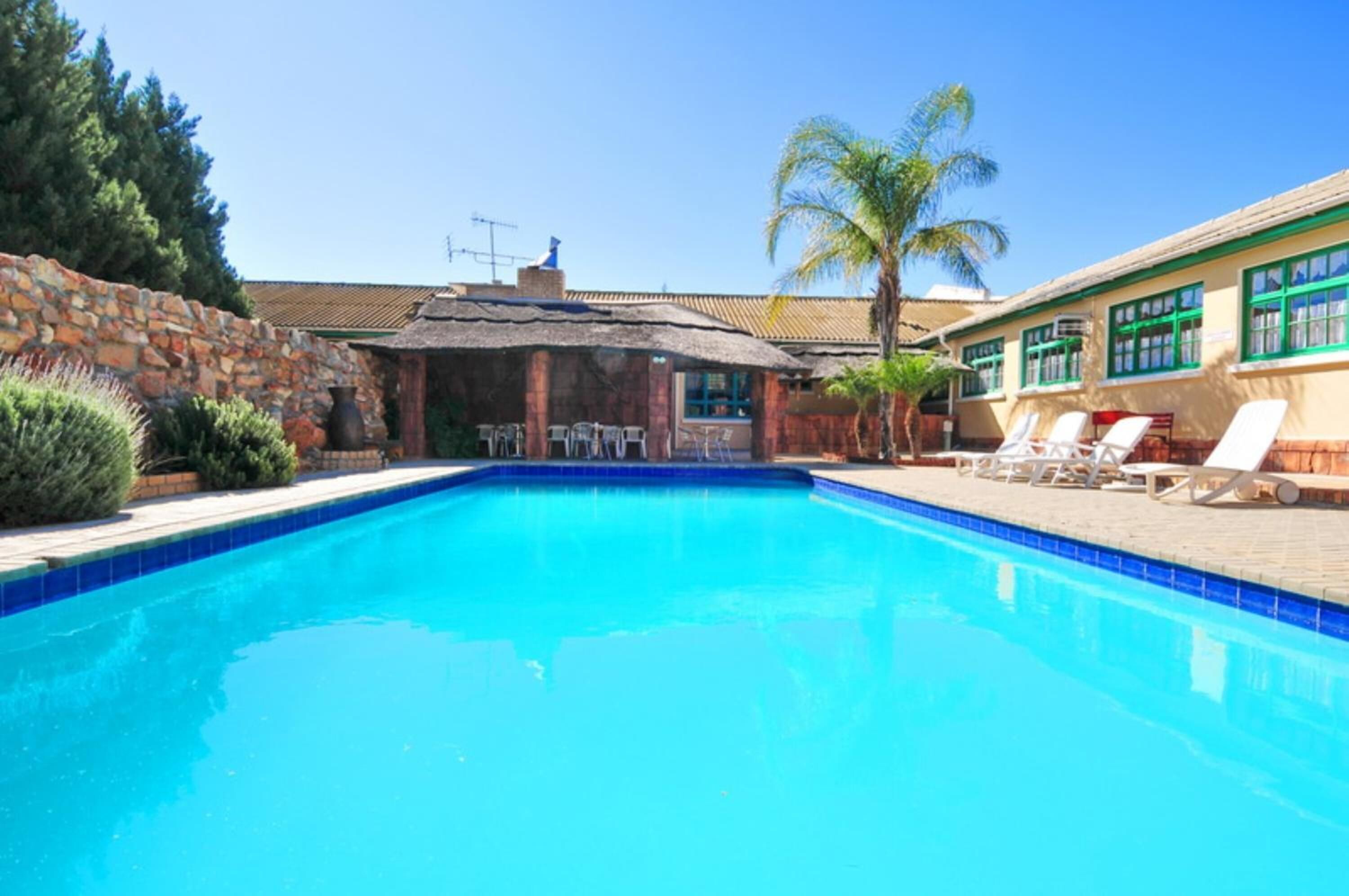 Een buitenzwembad, parasols bij het zwembad en ligstoelen