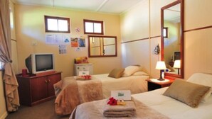 A hotel room with two beds, a television, a desk, and a mirror. - Oasis Country Lodge (Matzikama)