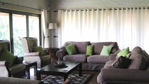 A living room with a sofa, armchairs, a coffee table, and a lamp. - Leselo La Bontshi Lodge (Groblersdal)