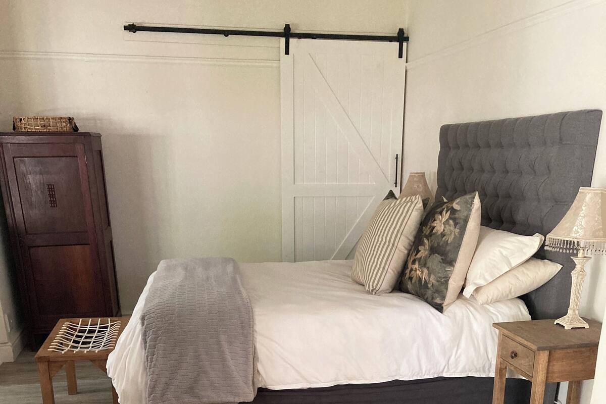A bedroom with a bed, a nightstand, a wooden cabinet, and a patterned rug.