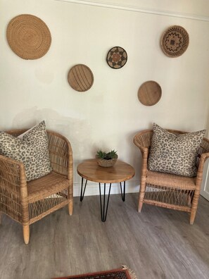 A room with two wicker chairs, a small wooden table, and several woven wall decorations. - Happy Lands Self Catering B&B (Addo)