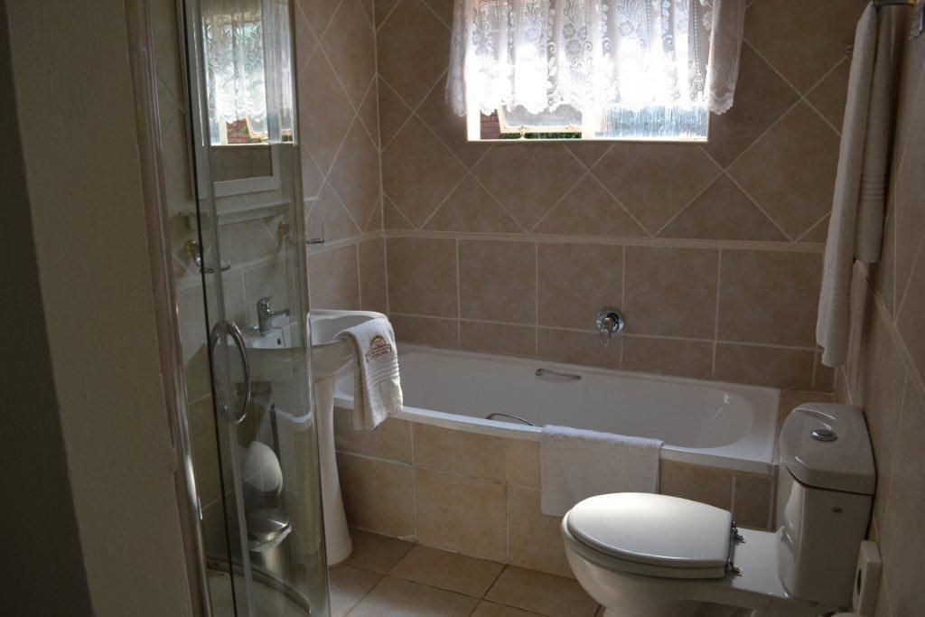 A bathroom with a bathtub, toilet, and glass shower enclosure.
