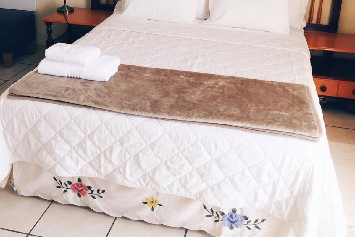 Una cama bien hecha con colcha acolchada y una manta marrón.