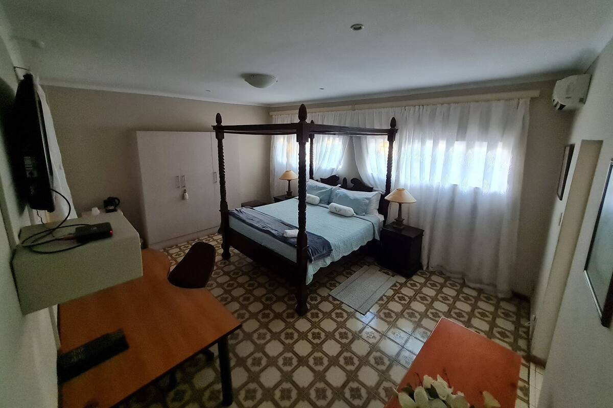 Una habitación con cama con dosel, escritorio, silla y televisor.