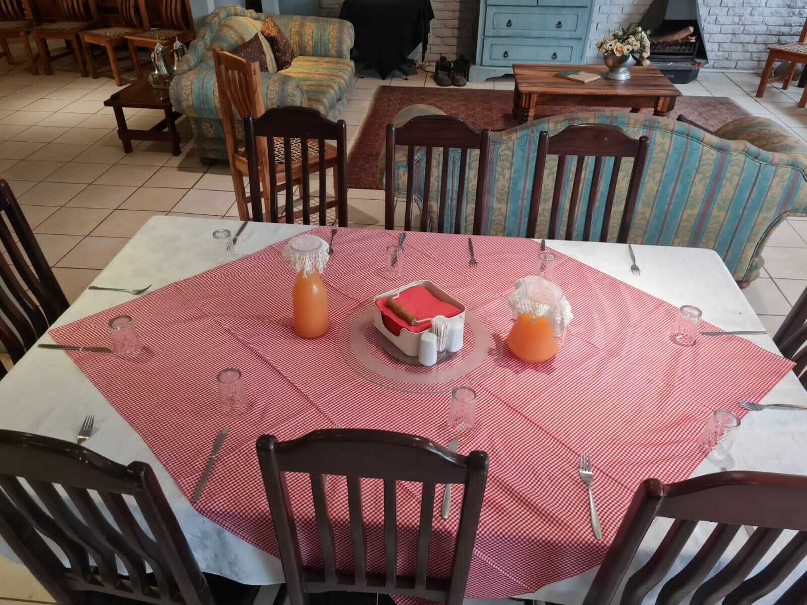 Un comedor con una mesa dispuesta para cuatro personas, rodeada de sillas de madera.