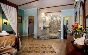 Ein Zimmer mit Bett, einem Badezimmer mit Dusche und einem Essbereich mit Tisch und Stühlen.
