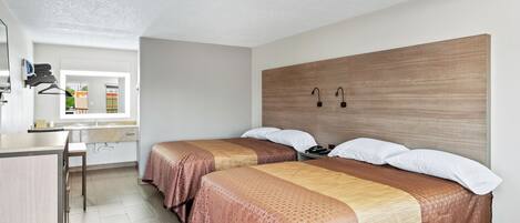 Una habitación de hotel con dos camas, un escritorio y una ventana.