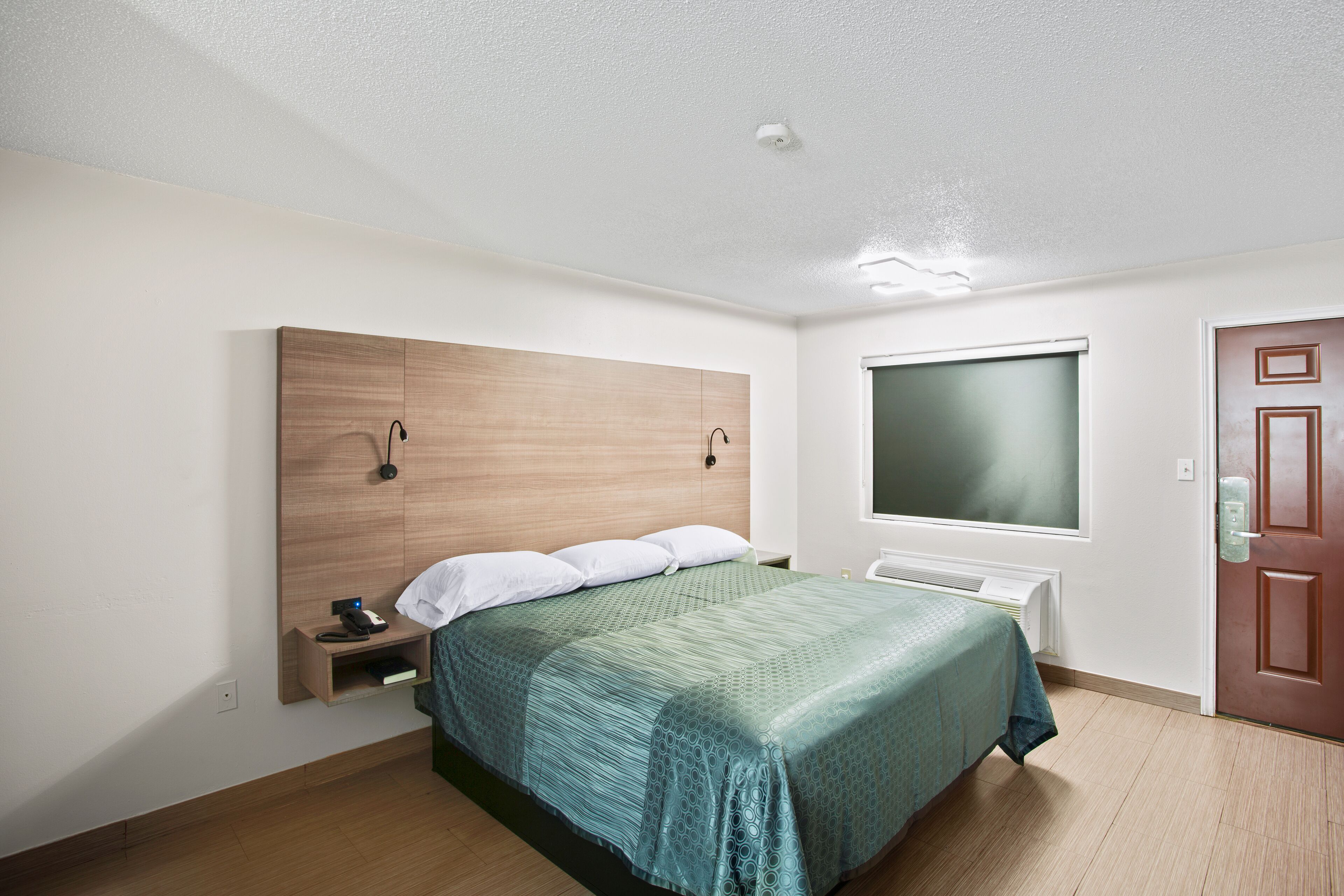 Une chambre à coucher avec un lit, une table de chevet et une fenêtre.