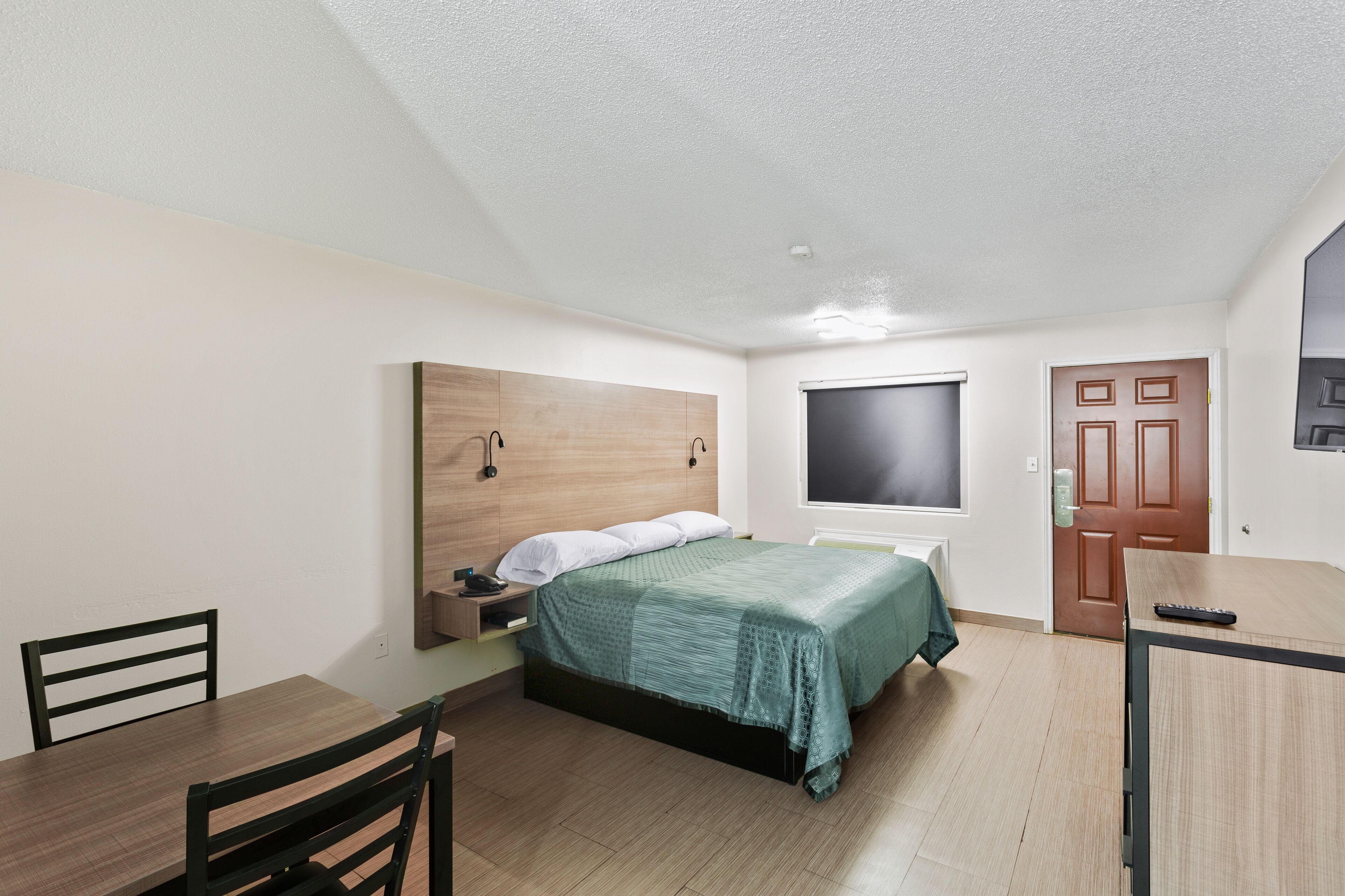 A bedroom with a bed, bedside table, and a desk with a chair.