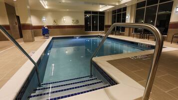 An indoor swimming pool with a lifeguard chair, pool lift, and no diving sign.