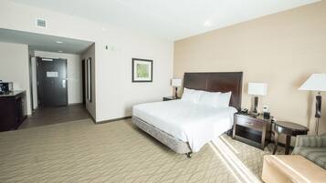 A hotel room with a large bed, bedside tables with lamps, a small desk, and a chair.