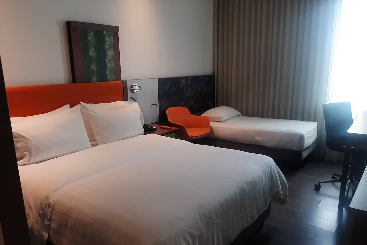 Une chambre d’hôtel avec deux lits, un bureau et une chaise.