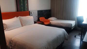 Habitación de hotel con dos camas, un escritorio y una silla.
