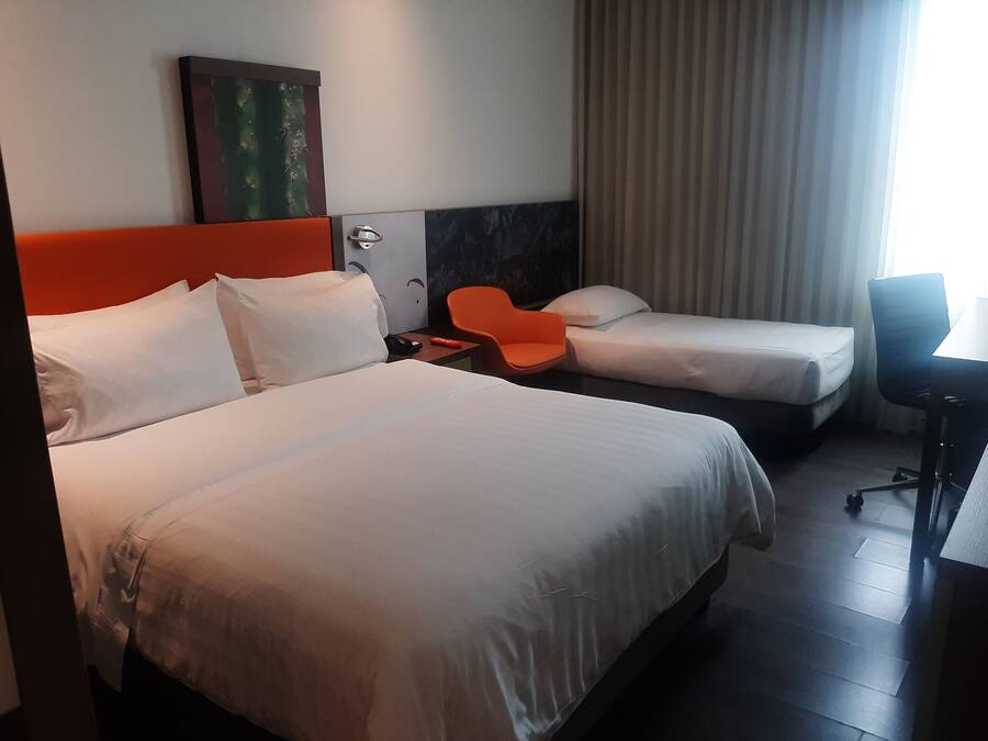 Habitación de hotel con dos camas, un escritorio y una silla.