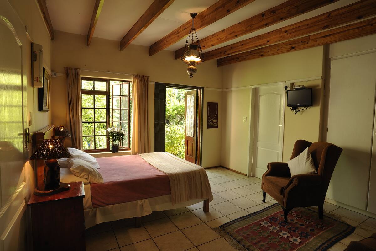 Een slaapkamer met een bed, een stoel, een televisie en een raam met gordijnen.
