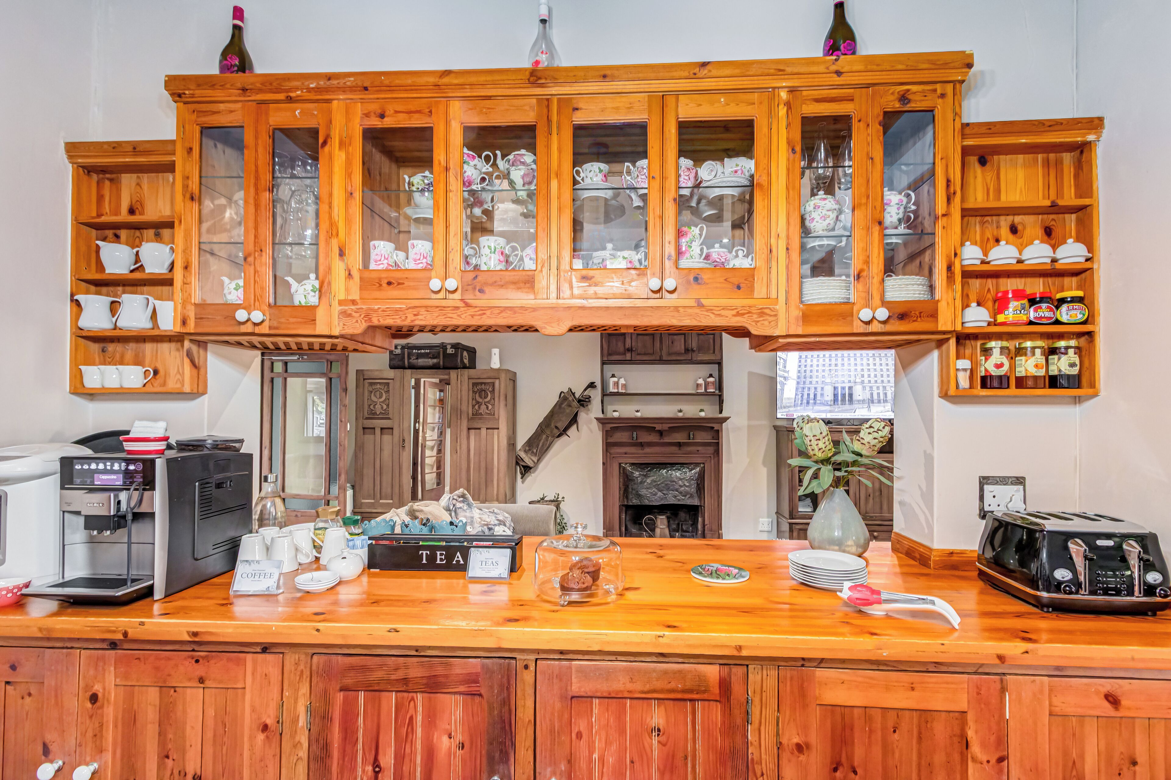 A wooden counter with a coffee machine, tea station, and a vintage radio.