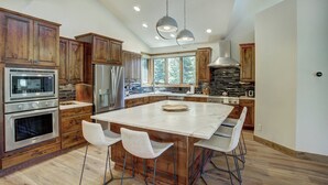 A spacious kitchen with wooden cabinets, stainless steel appliances, and a large island with bar stools. - Keystone Private Homes by Vail Resorts (Keystone)