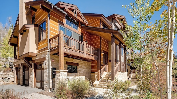 A multi-story log cabin with a balcony, stone foundation, and a stone chimney. - Keystone Private Homes by Vail Resorts (Keystone)