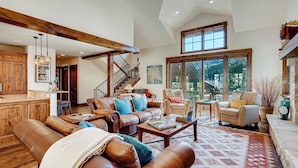 A spacious living area with leather sofas, a coffee table, and a large window providing a view of the outdoors. - Keystone Private Homes by Vail Resorts (Keystone)