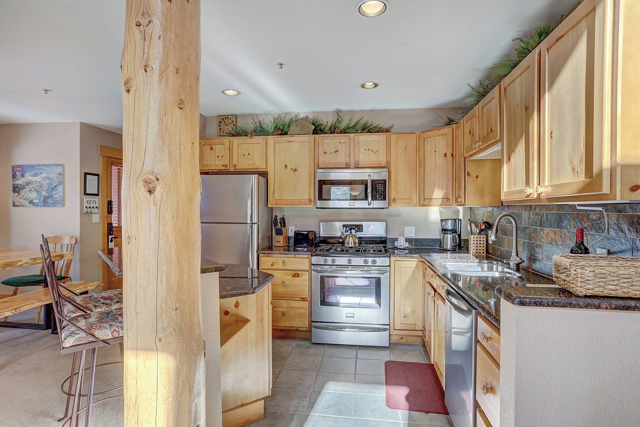 A kitchen with wooden cabinets, stainless steel appliances, and a dining area with a table and chairs.