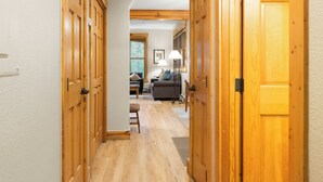 A hallway with wooden doors leading to a living area with a sofa and lamp. - East Keystone by Vail Resorts (Keystone)