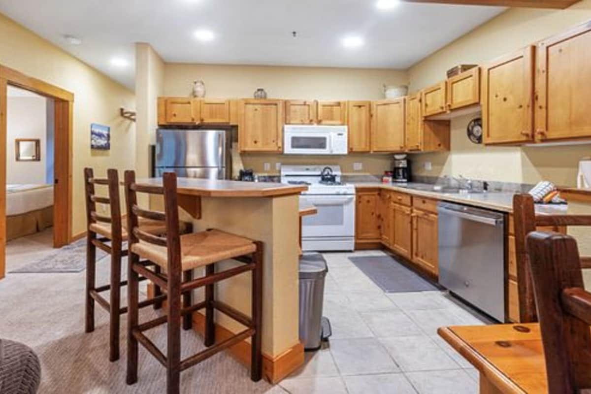 A compact kitchen with wooden cabinets, a central island, and a dining area with chairs.