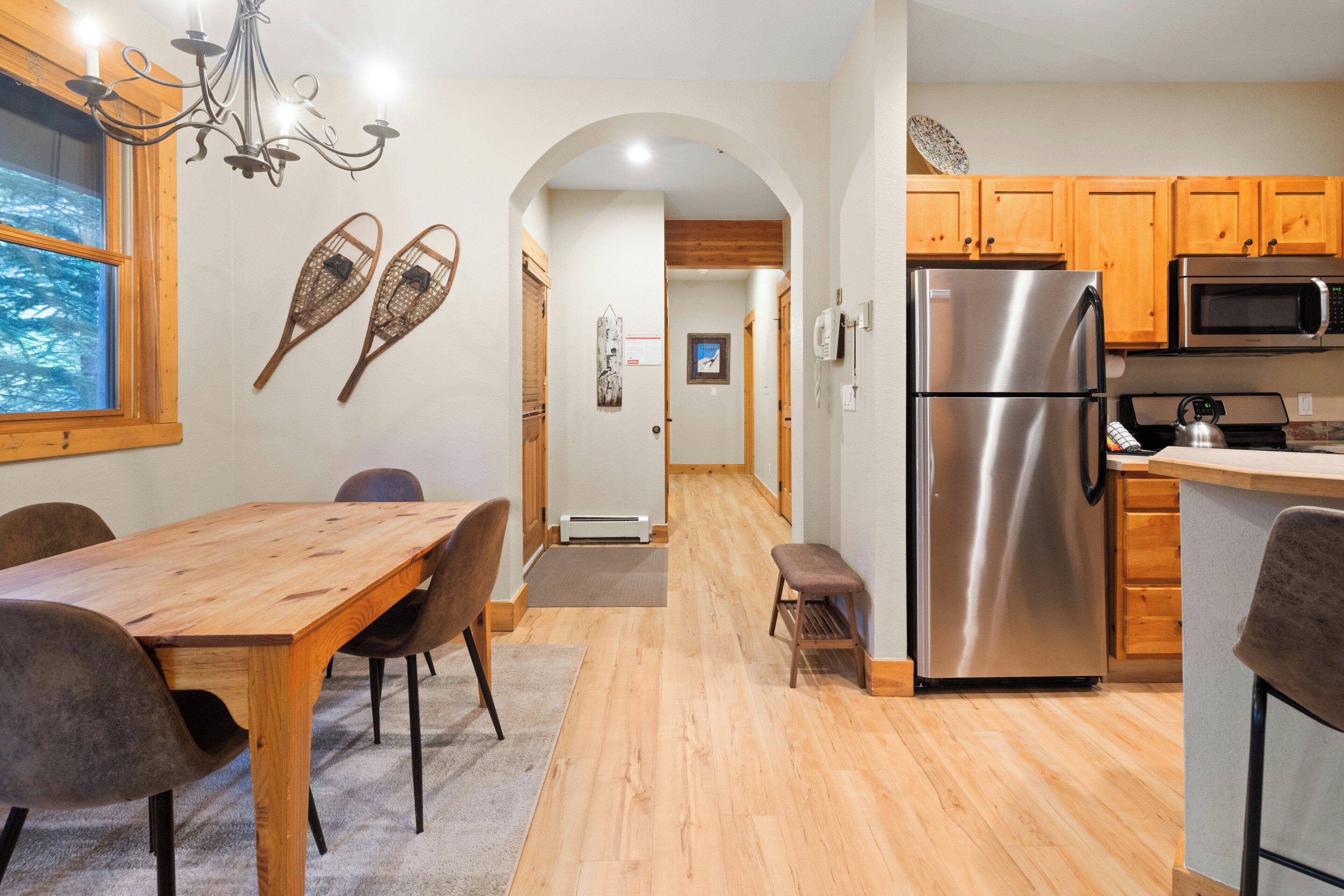 A modern kitchen with wooden cabinets, a stainless steel refrigerator, and a microwave.