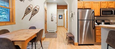 A modern kitchen with wooden cabinets, a stainless steel refrigerator, and a microwave.