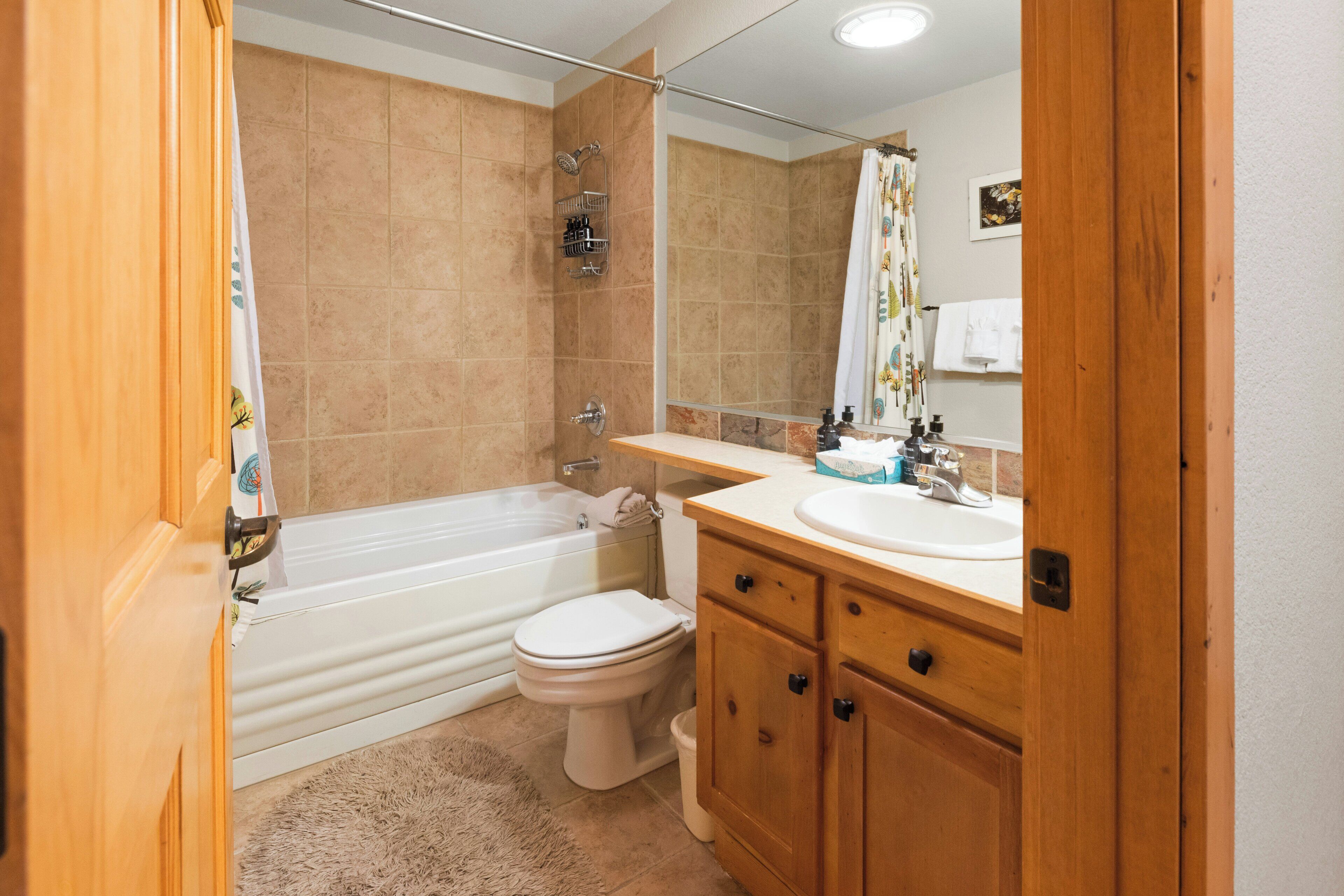 Un baño con bañera, inodoro y tocador con espejo.