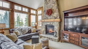 A cozy living room with a stone fireplace, a large flat-screen TV, and a leather sofa. - East Keystone by Vail Resorts (Keystone)