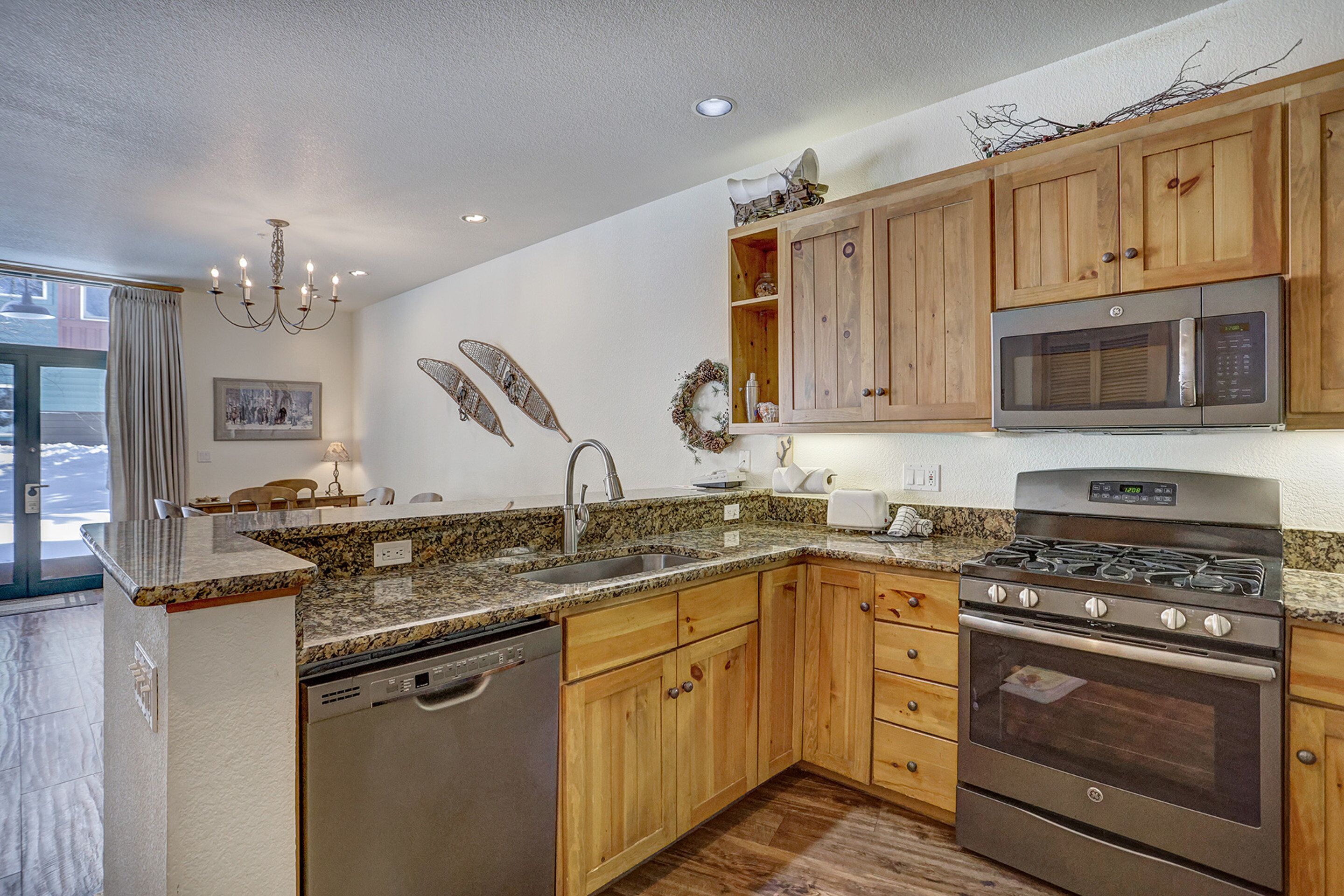 A modern kitchen with wooden cabinets, a stainless steel dishwasher, a built-in oven, and a microwave.