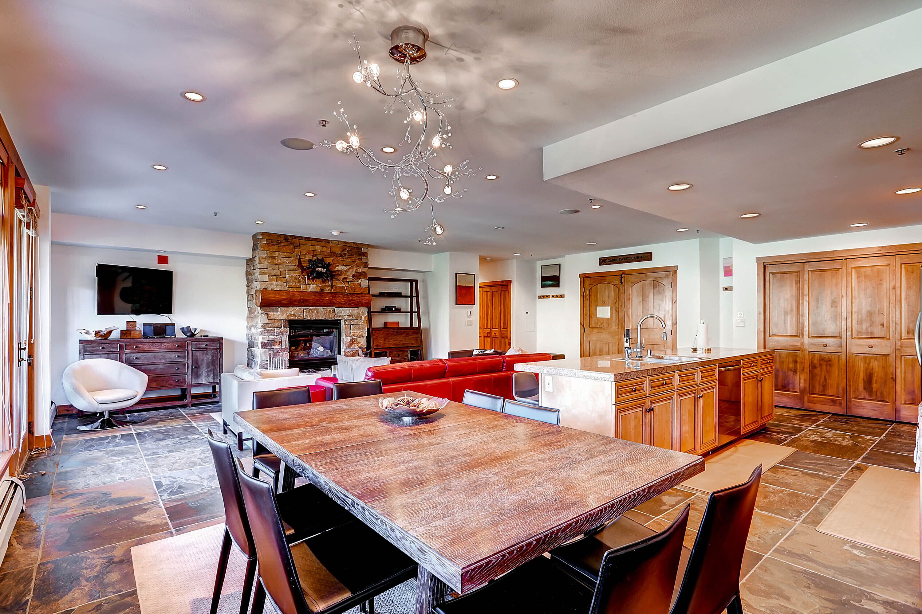 A spacious kitchen with a large wooden table, modern appliances, and a stone fireplace.